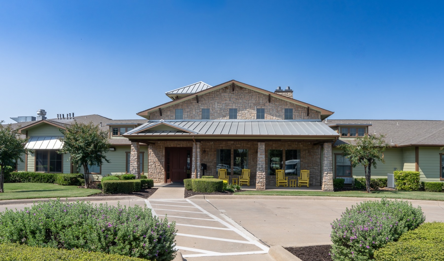 a brick building with yellow rocking chairs on the front porch